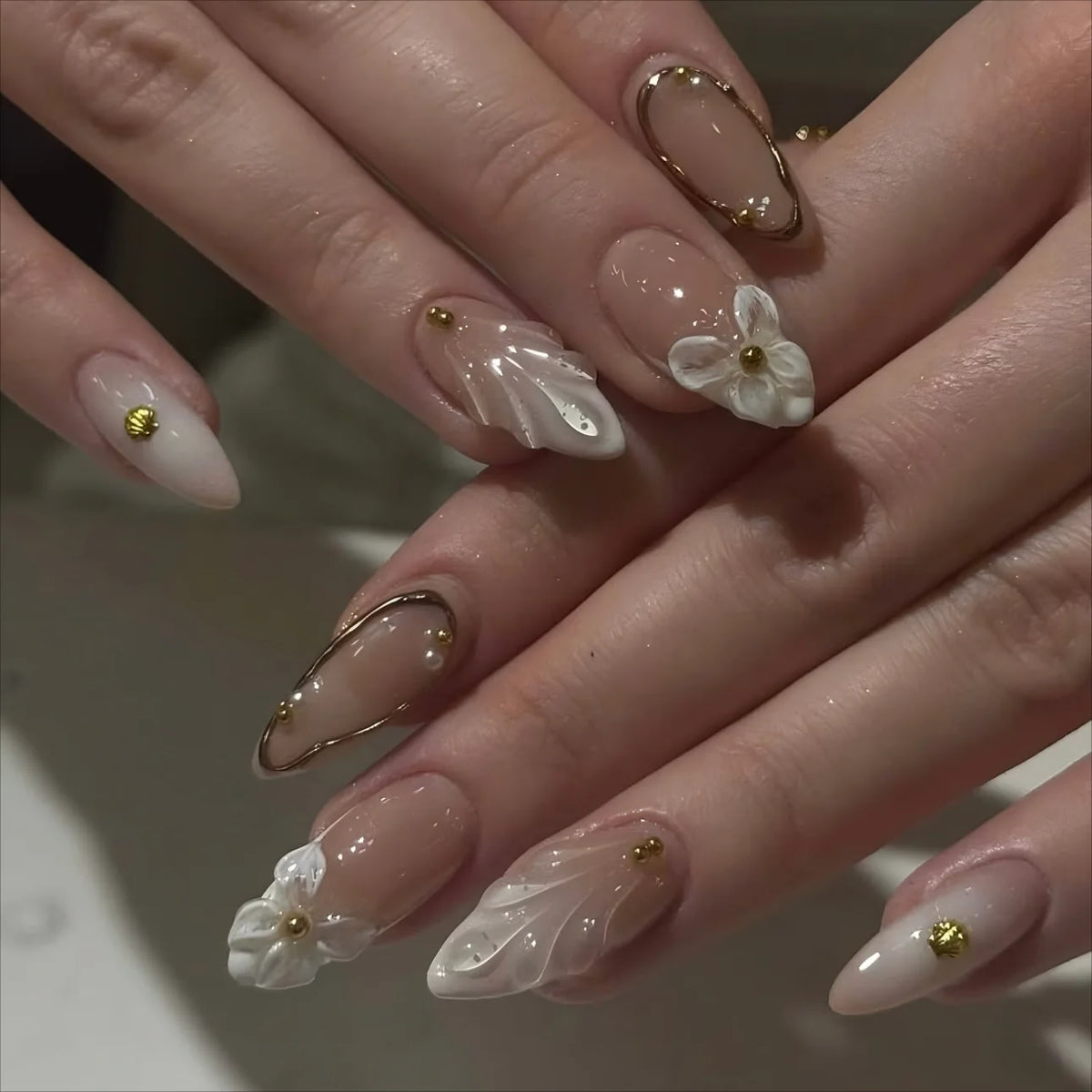 Decorative floral and embellished nail designs shown on hands