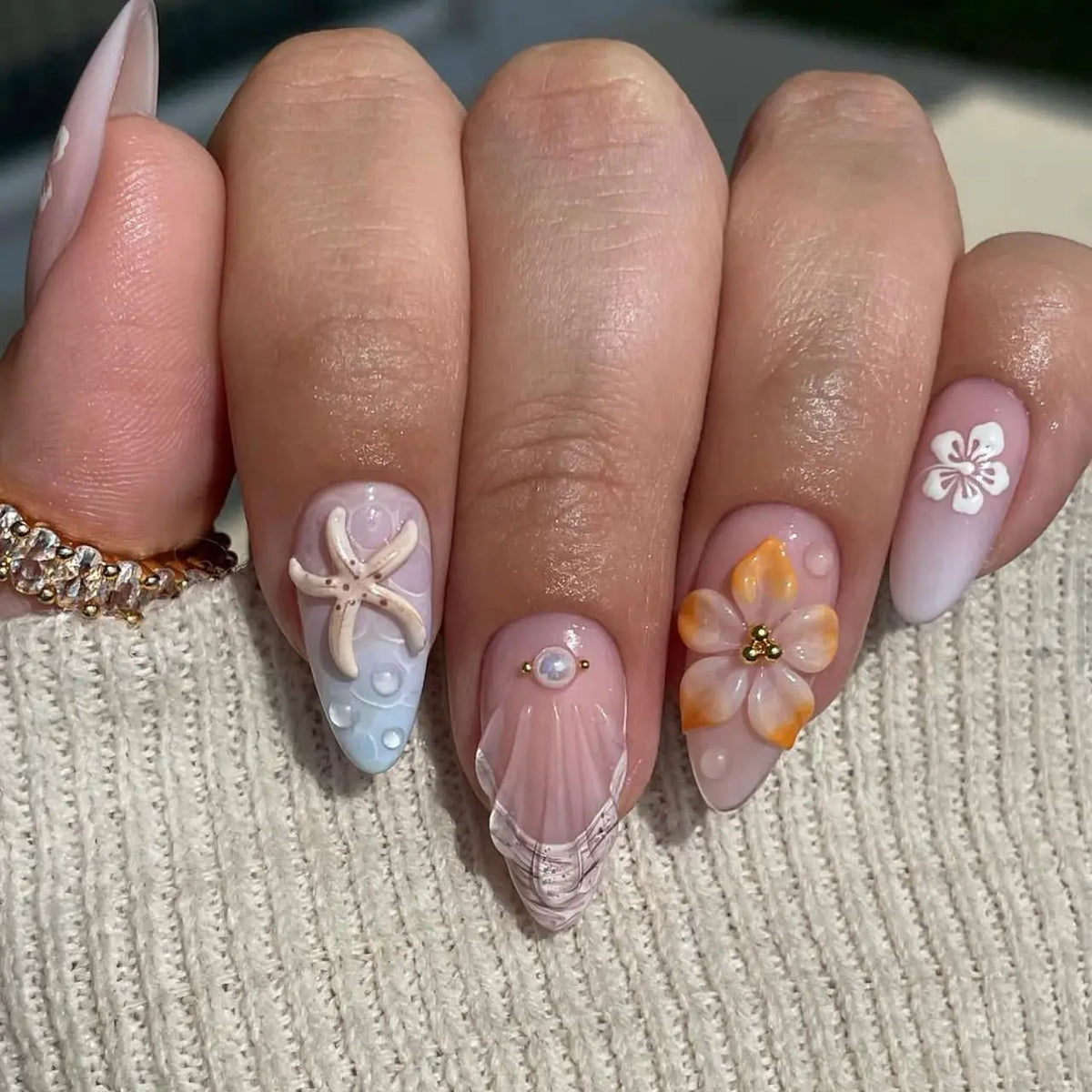 Decorative floral and embellished nail designs shown on hands