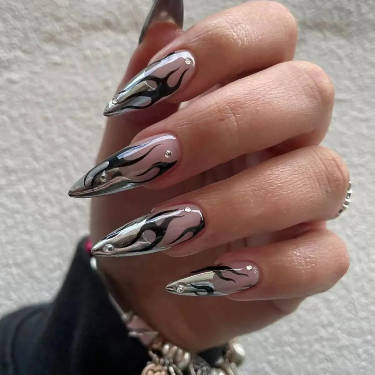 Long pointed nail designs with dark and metallic accents shown on hands