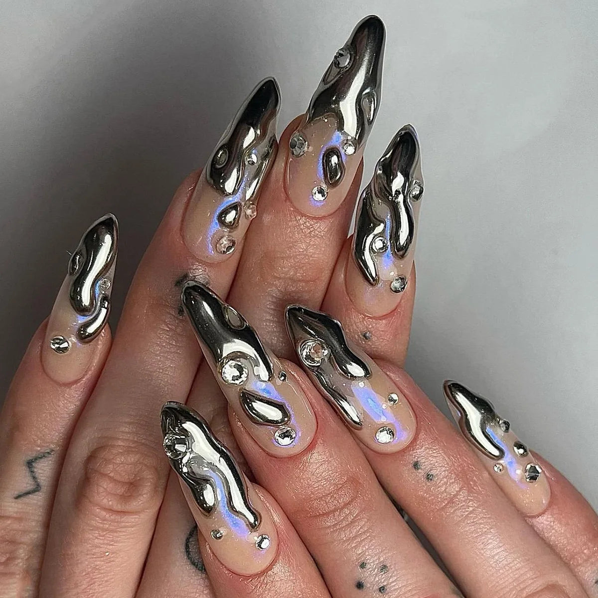 Long embellished pointed nail designs shown on hands