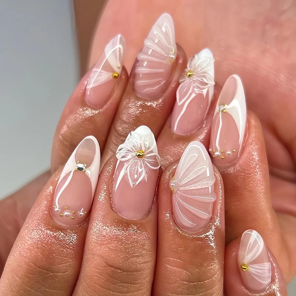 Decorative floral and embellished nail designs shown on hands