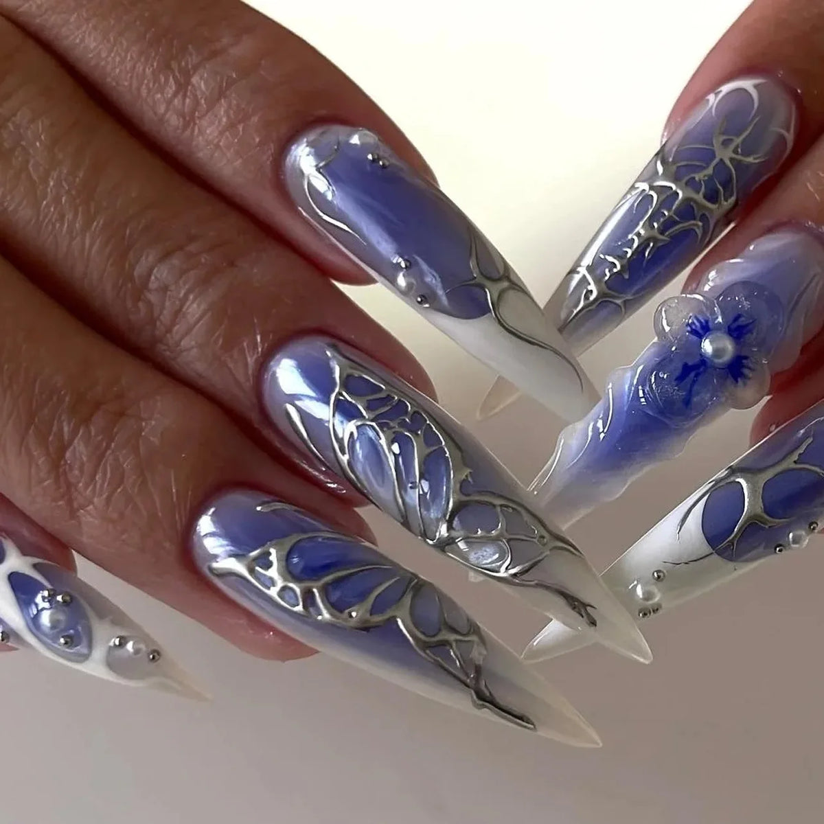 Decorative nail designs with floral, metallic or gem accents shown on hands