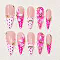 Pink pointed press-on nails with floral decorations arranged in rows