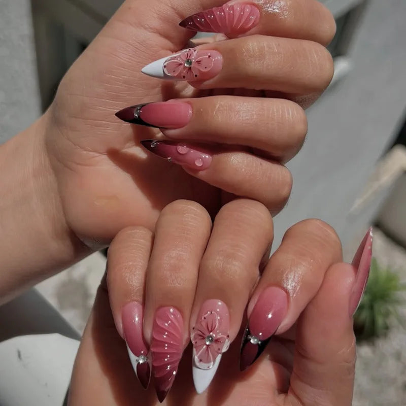 Long embellished pointed nail designs shown on hands