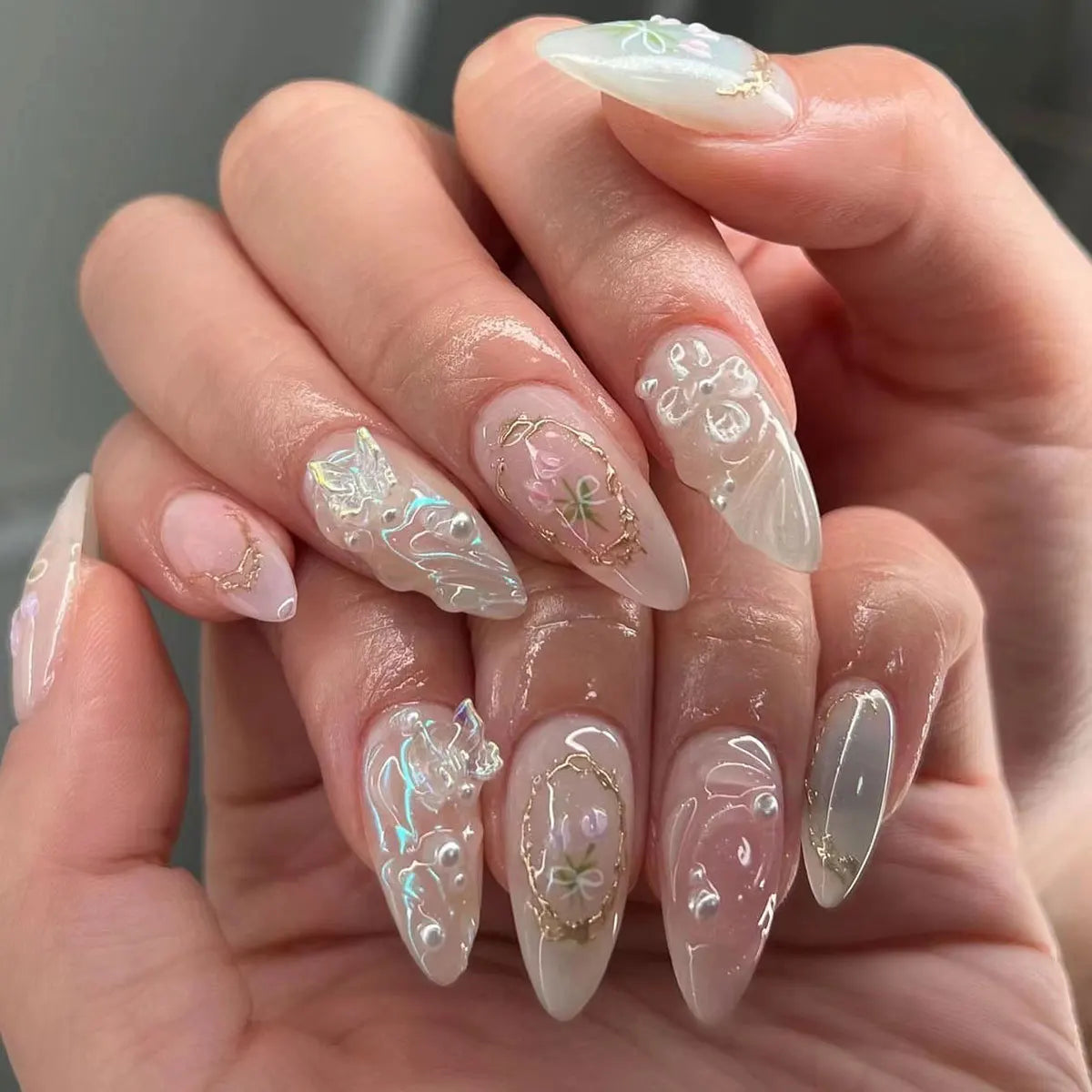 Decorative nail designs with floral, metallic or gem accents shown on hands