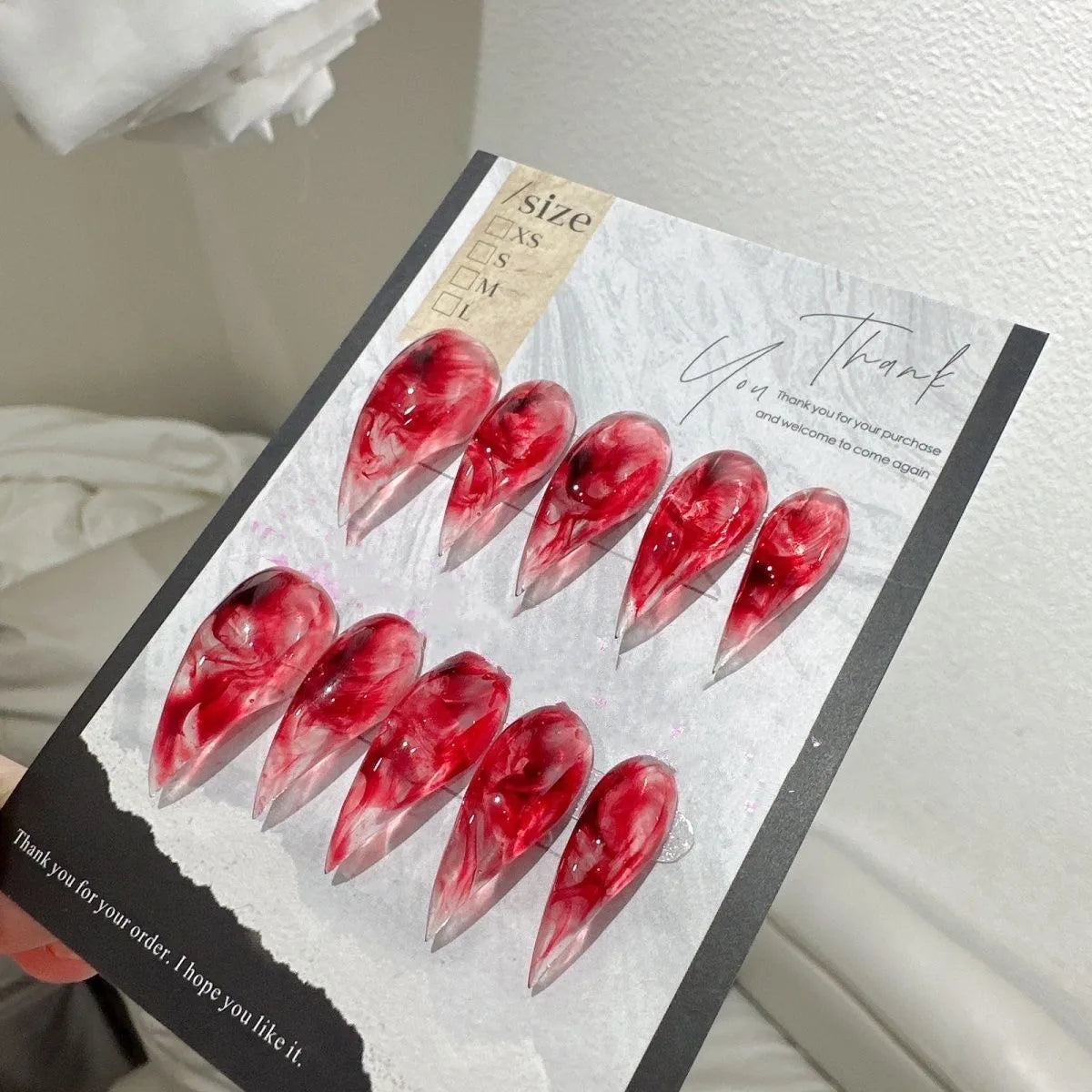 Red pointed press-on nails in a case