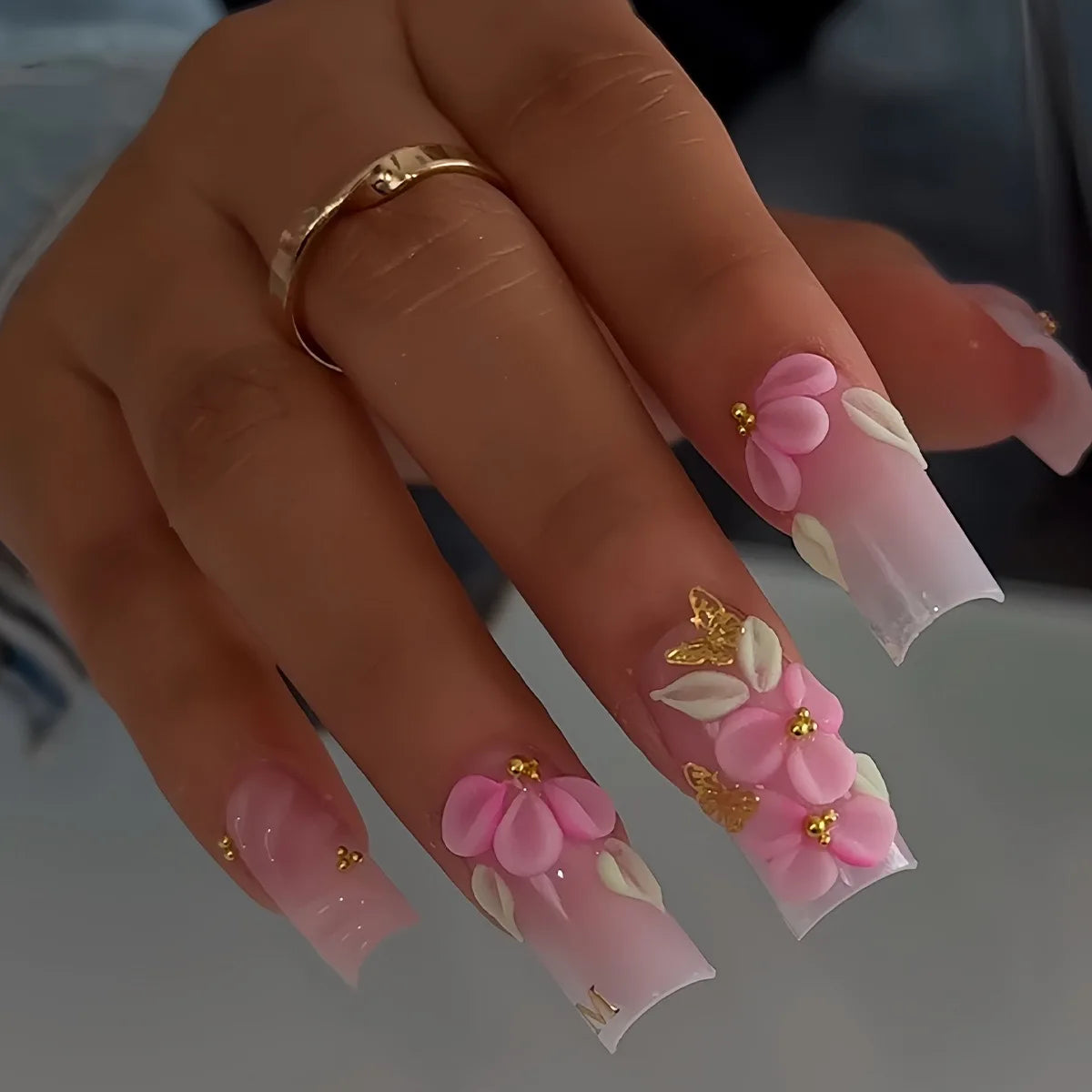 Decorative nail designs with floral, metallic or gem accents shown on hands
