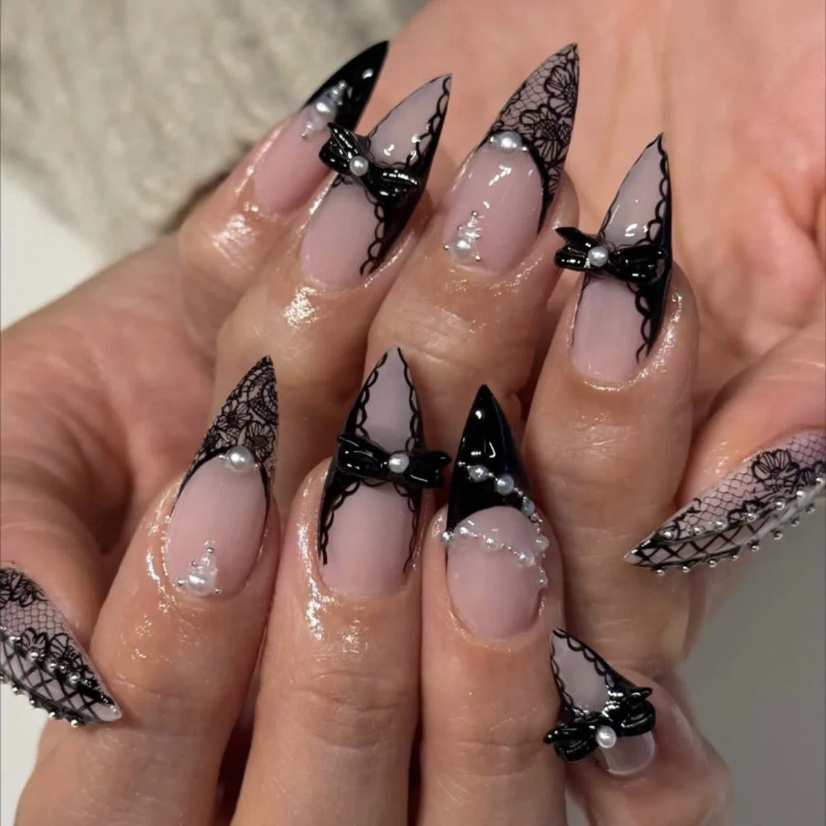 Long embellished pointed nail designs shown on hands