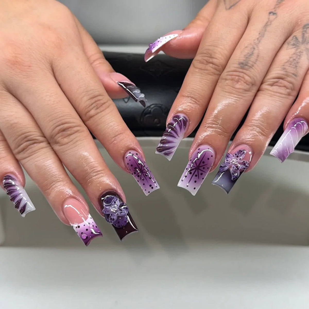 Decorative nail designs with floral, metallic or gem accents shown on hands