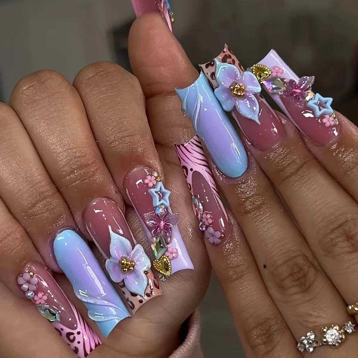 Decorative nail designs with floral, metallic or gem accents shown on hands