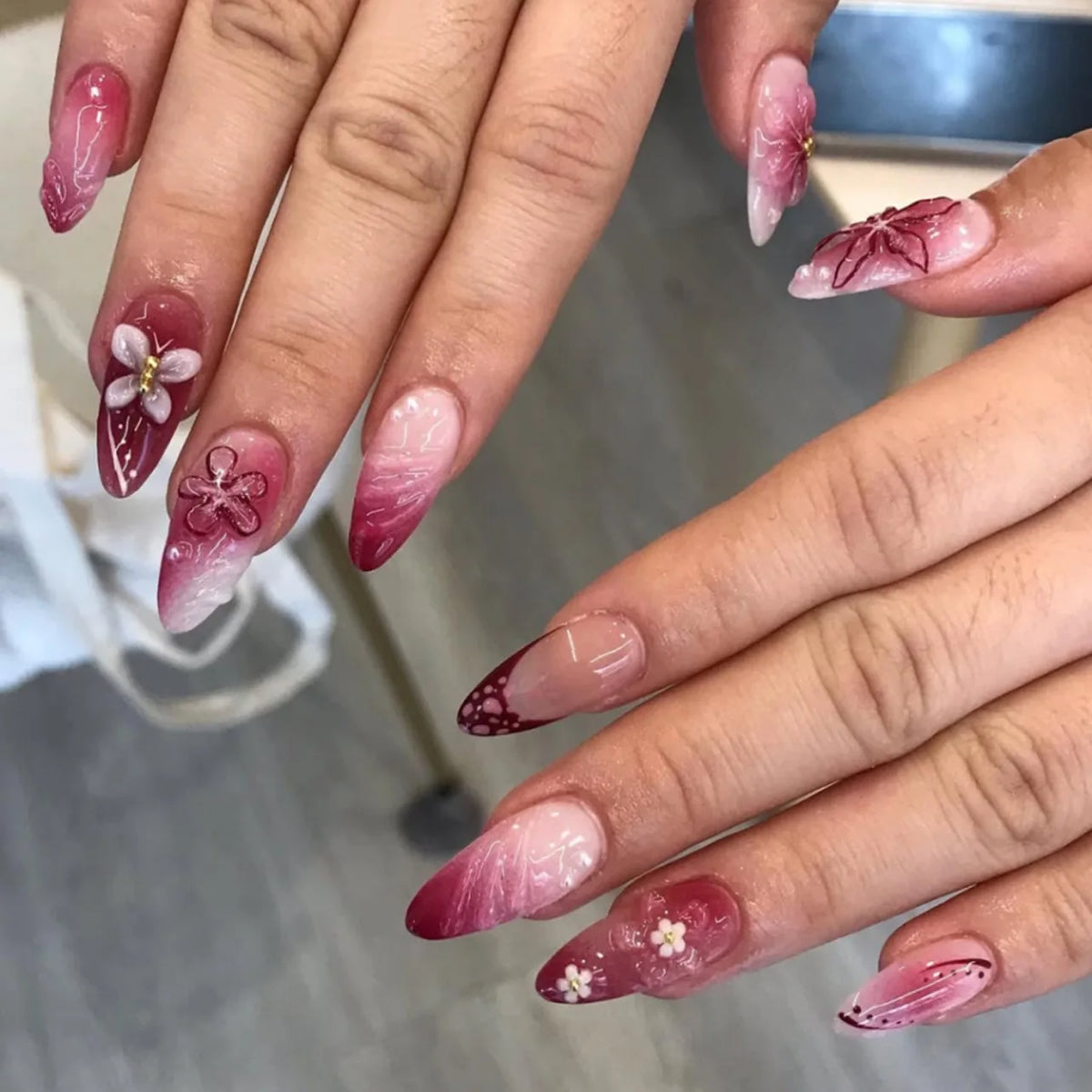 Decorative floral and embellished nail designs shown on hands
