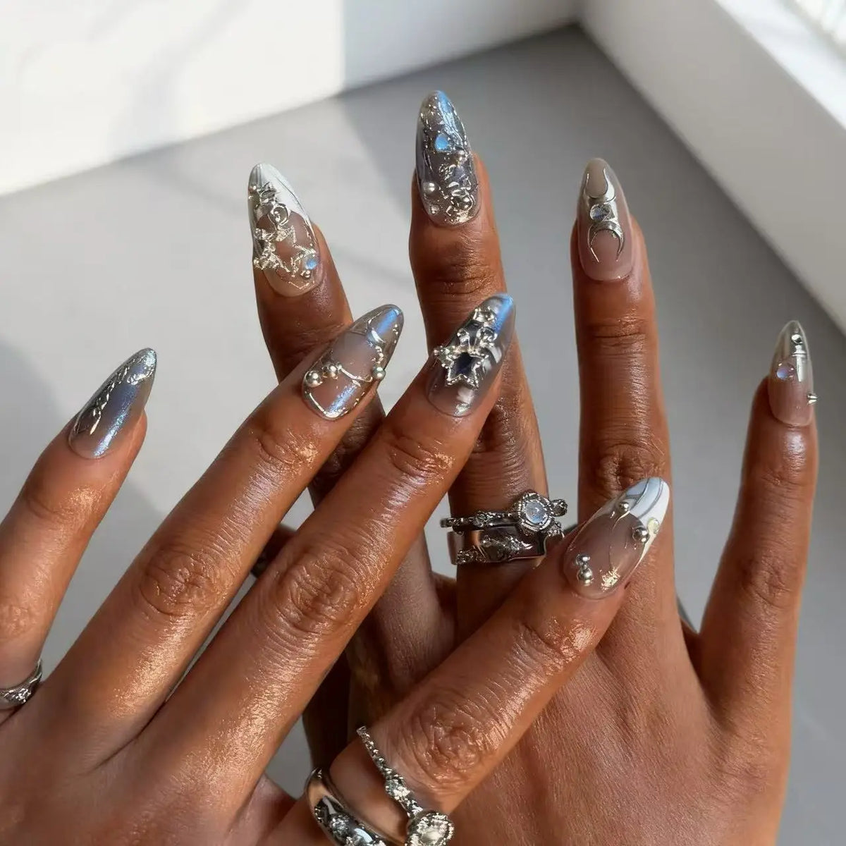 Metallic and embellished nails shown on hands