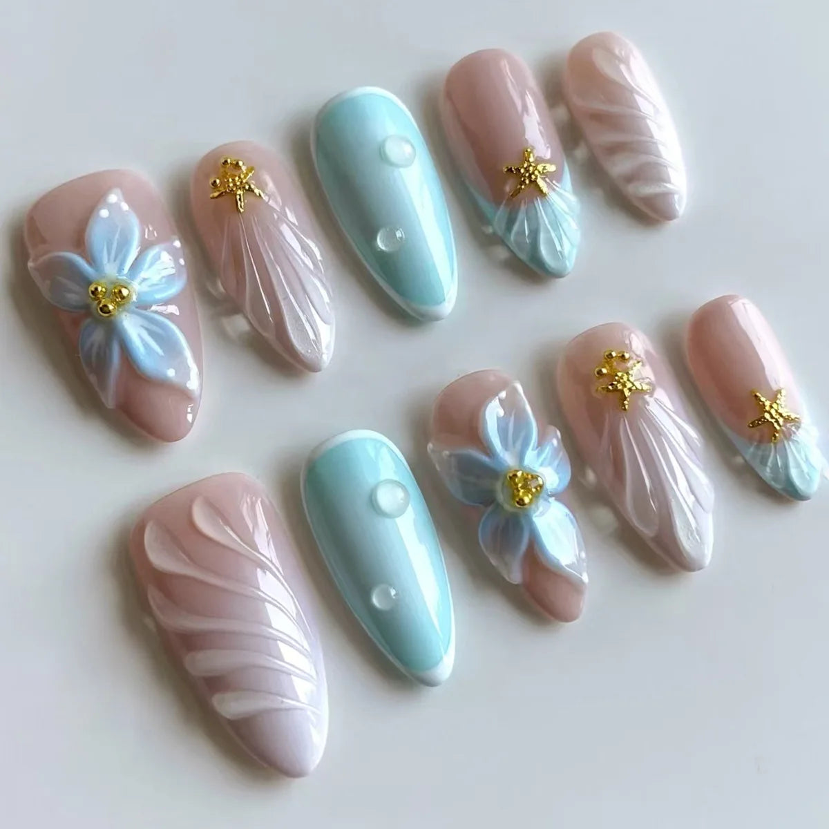 Blue and pink floral press-on nails arranged in rows