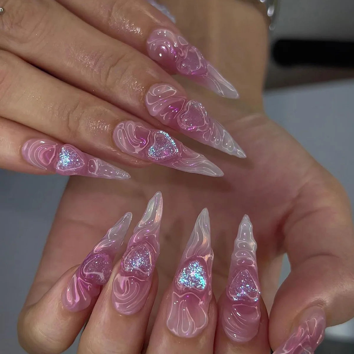 Decorative nail designs with floral, metallic or gem accents shown on hands